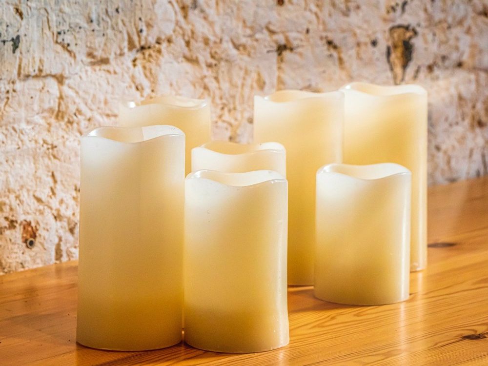 Different sizes of candles on the wooden shelve.