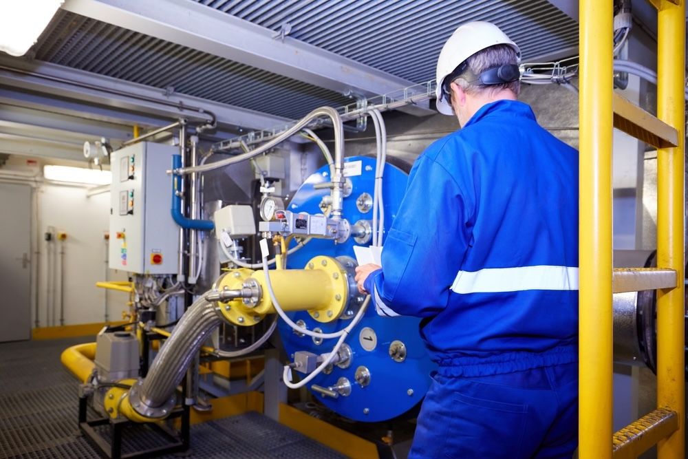 An engineer oversees industrial equipment as part of a predictive maintenance system. This approach helps businesses optimize resource use and reduce costs by ensuring equipment and cleaning tools are serviced and maintained efficiently, preventing unexpected downtime.