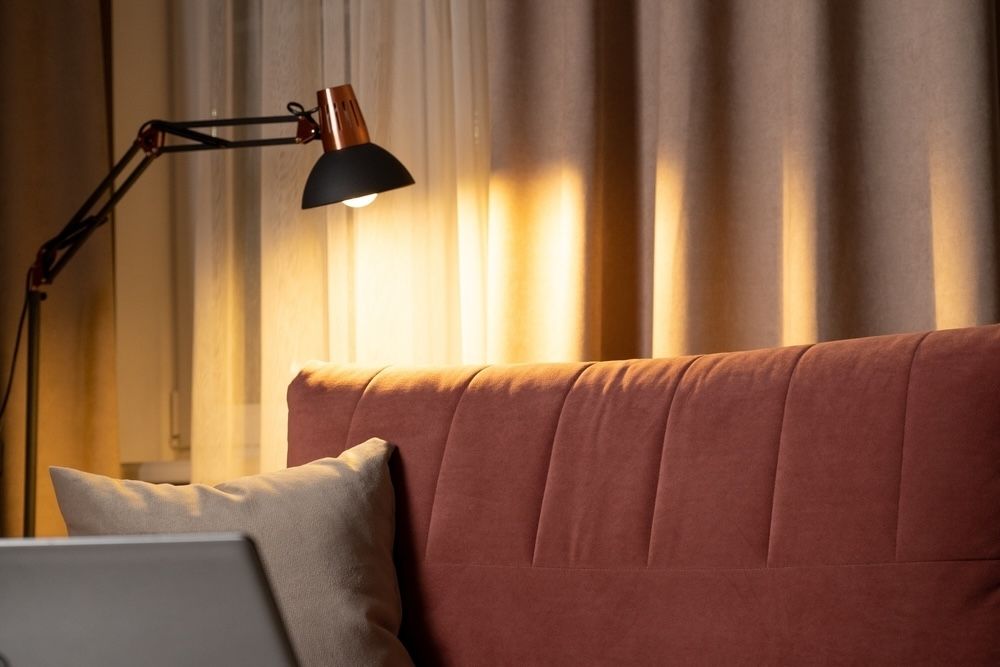 A well-placed lamp creates a soft, focused glow that is ideal for a cozy reading nook or a personal retreat. The warm light enhances the intimate feel of the corner while complementing the muted color palette, proving that lighting is key to setting the right mood.