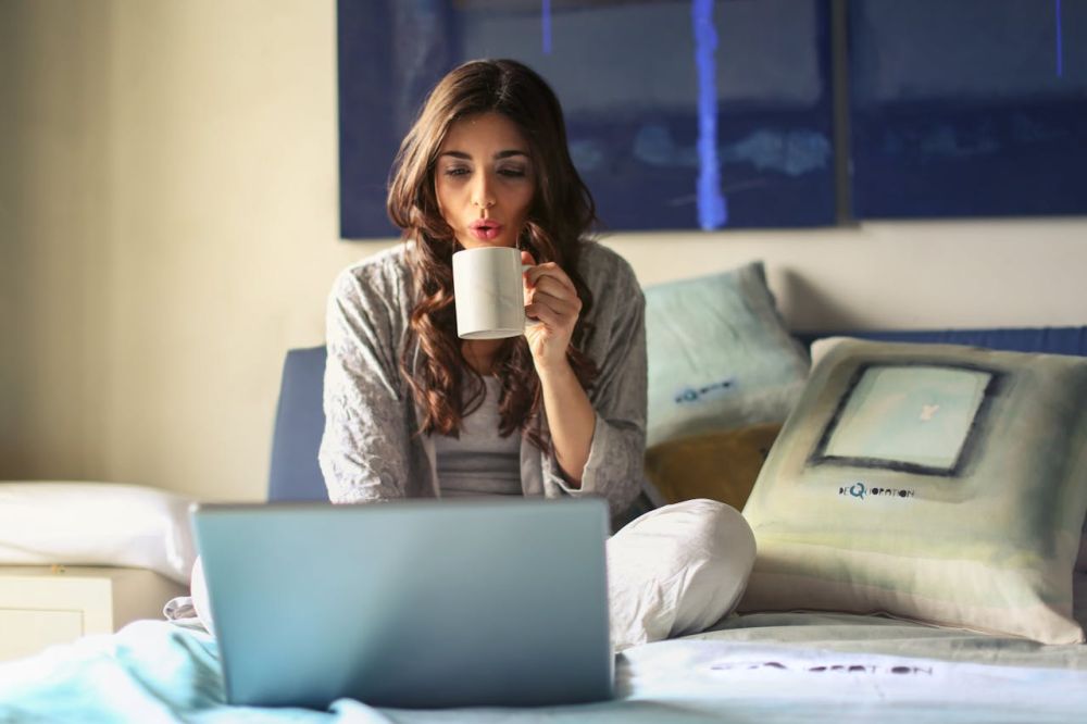 A girl working on her laptop. sipping coffee, and working.