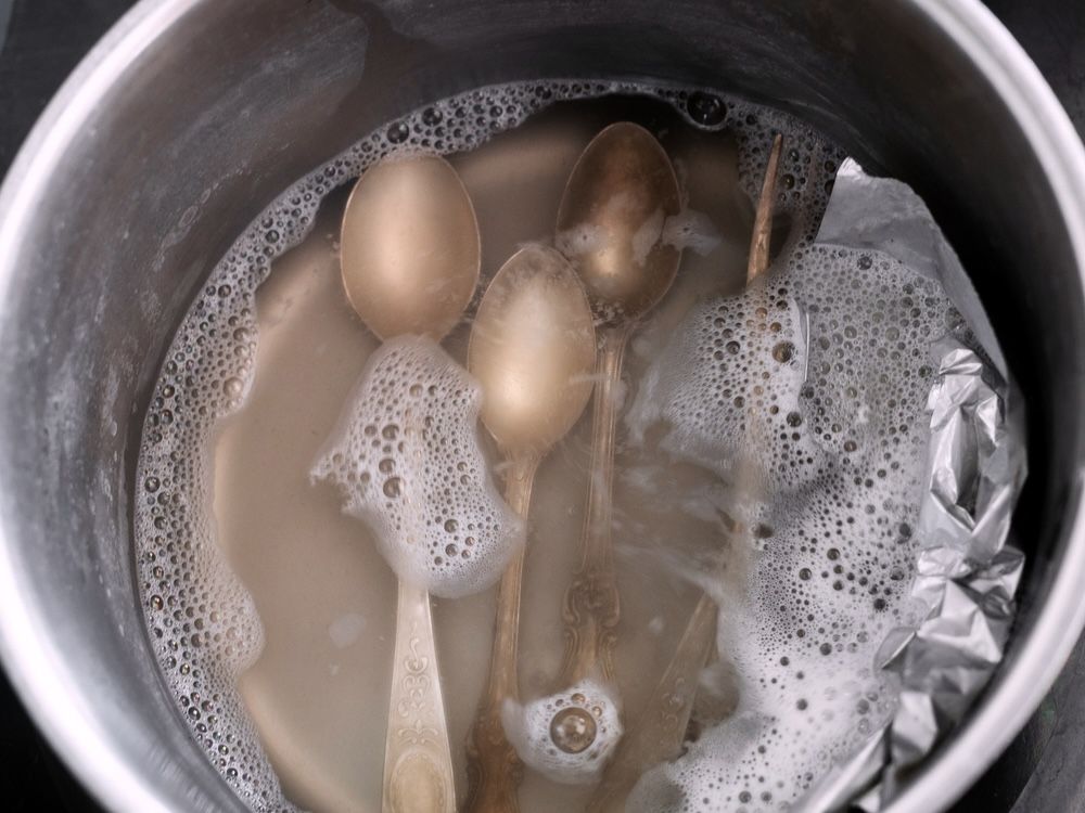 Silverware soaking in a baking soda solution to remove tarnish and restore shine.