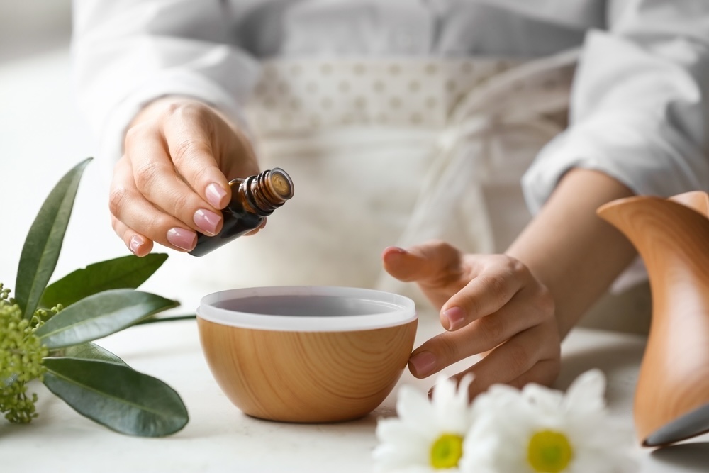 A person skillfully adds essential oil to a diffuser, enhancing their space with natural fragrances.