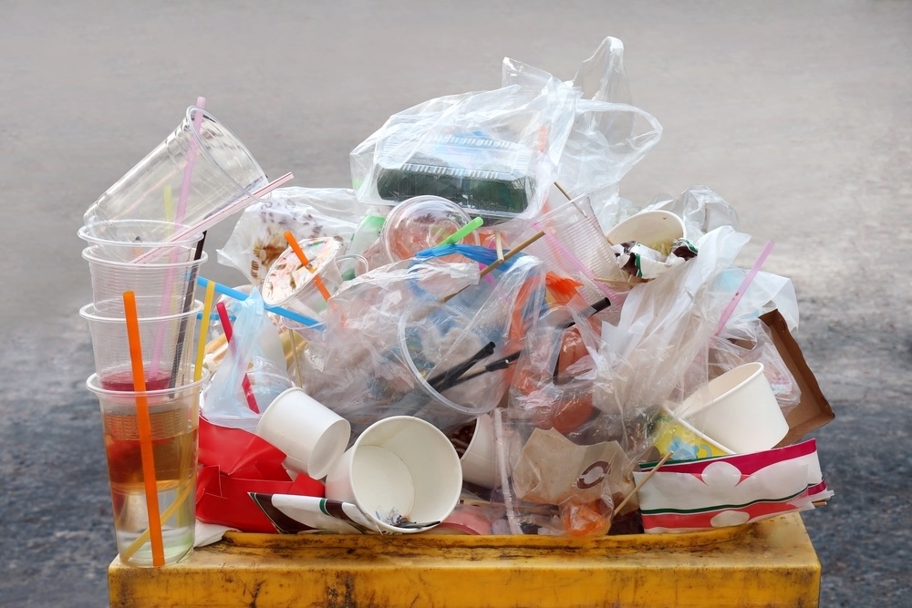 An overflowing bin of single-use plastics demonstrates the urgency of recycling.