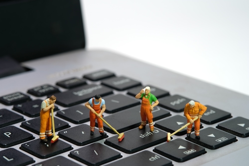A whimsical take on MacBook cleanliness, this image features miniature figurines 'cleaning' the keyboard, representing the attention to detail needed to keep the spaces between the keys free of debris and dust.