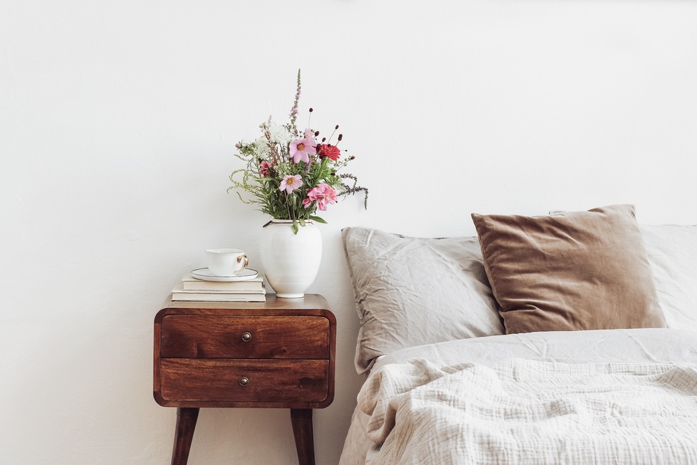 Simple Rustic Bedroom Bliss - This image captures the essence of minimalist rustic design, where simplicity and comfort take center stage. A vintage wooden bedside table, fresh flowers, and a cup of tea suggest a peaceful start to the day in a room that epitomizes relaxed living.